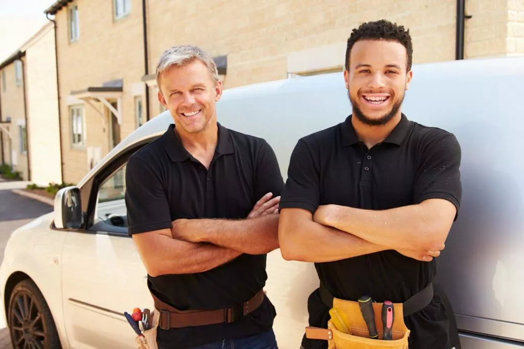 Portrait of a young and a middle aged tradesman by their van